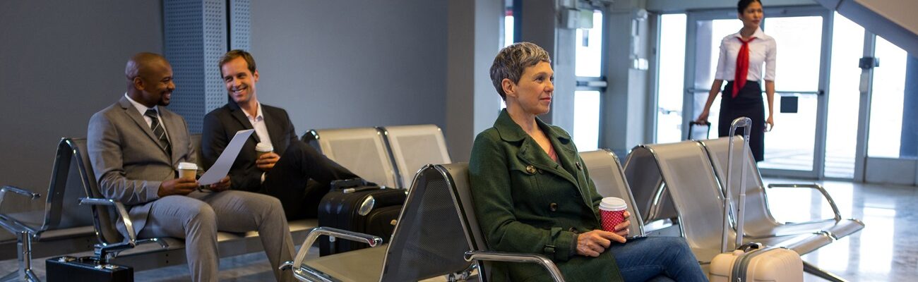 Woman sitting with luggage at waiting area in airport terminal